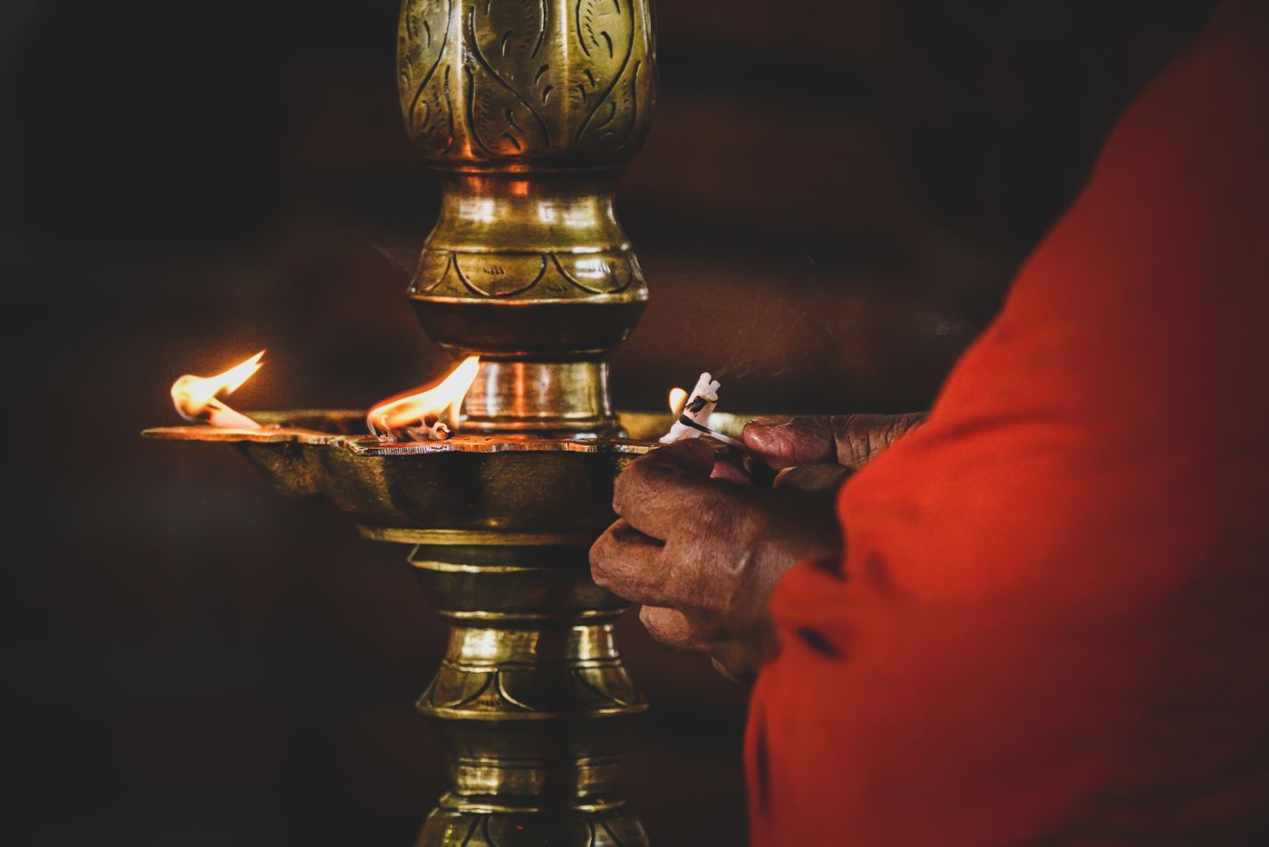 Hands lighting a traditional brass oil lamp