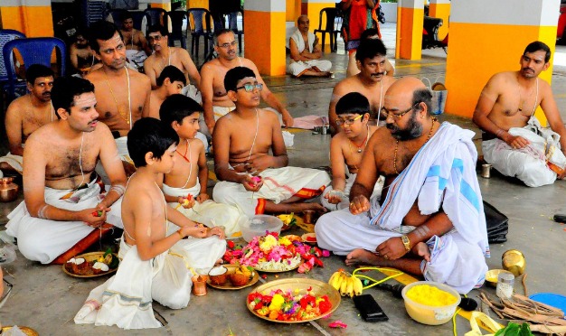 A senior priest teaching young boys ritual procedure in a group